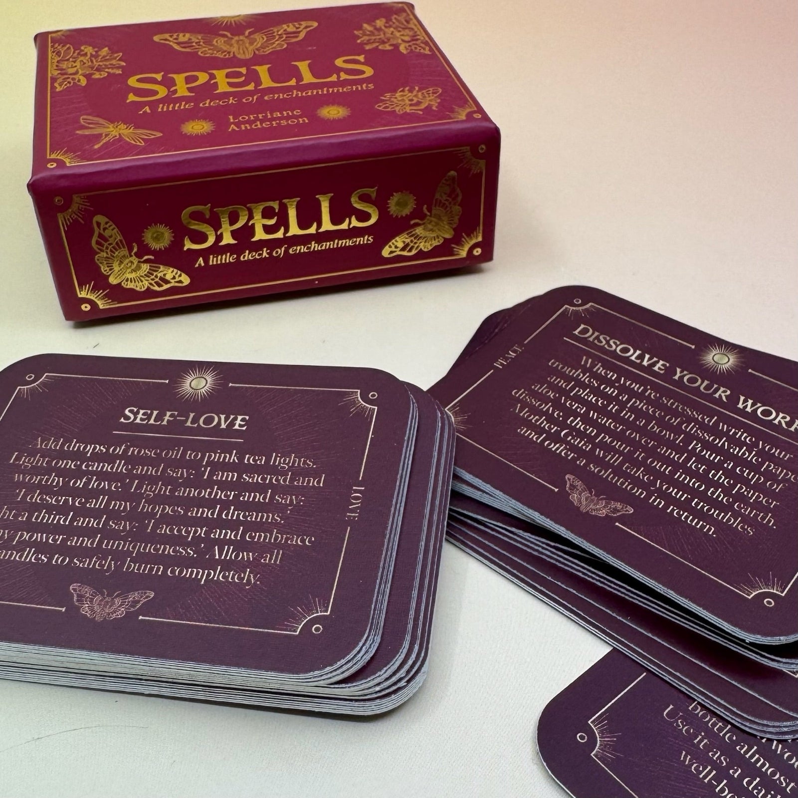 The Spells A Little Deck of Enchantment Spell Deck on a pink and yellow background, showing its contents.