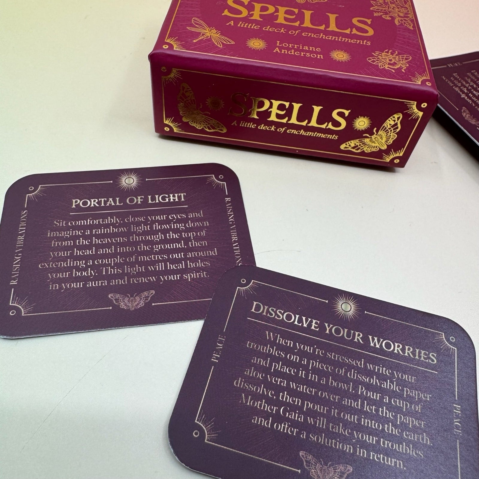 The Spells A Little Deck of Enchantment Spell Deck on a pink and yellow background, showing its contents.