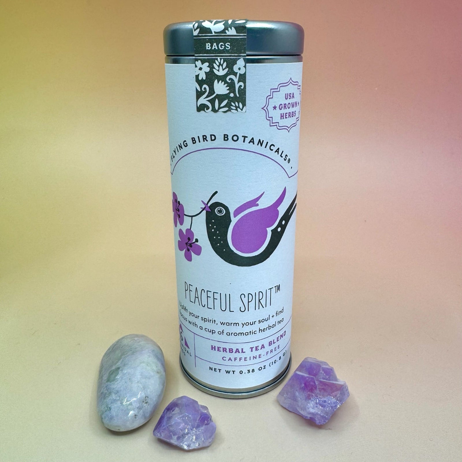 The Peaceful Spirit 6 Tea Bag Tin on a pink and yellow background surrounded by small crystals.