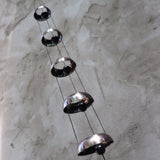 Someone holding the Copper Quintet Woodstock Temple Bells Wind Chime in front of a concrete wall.