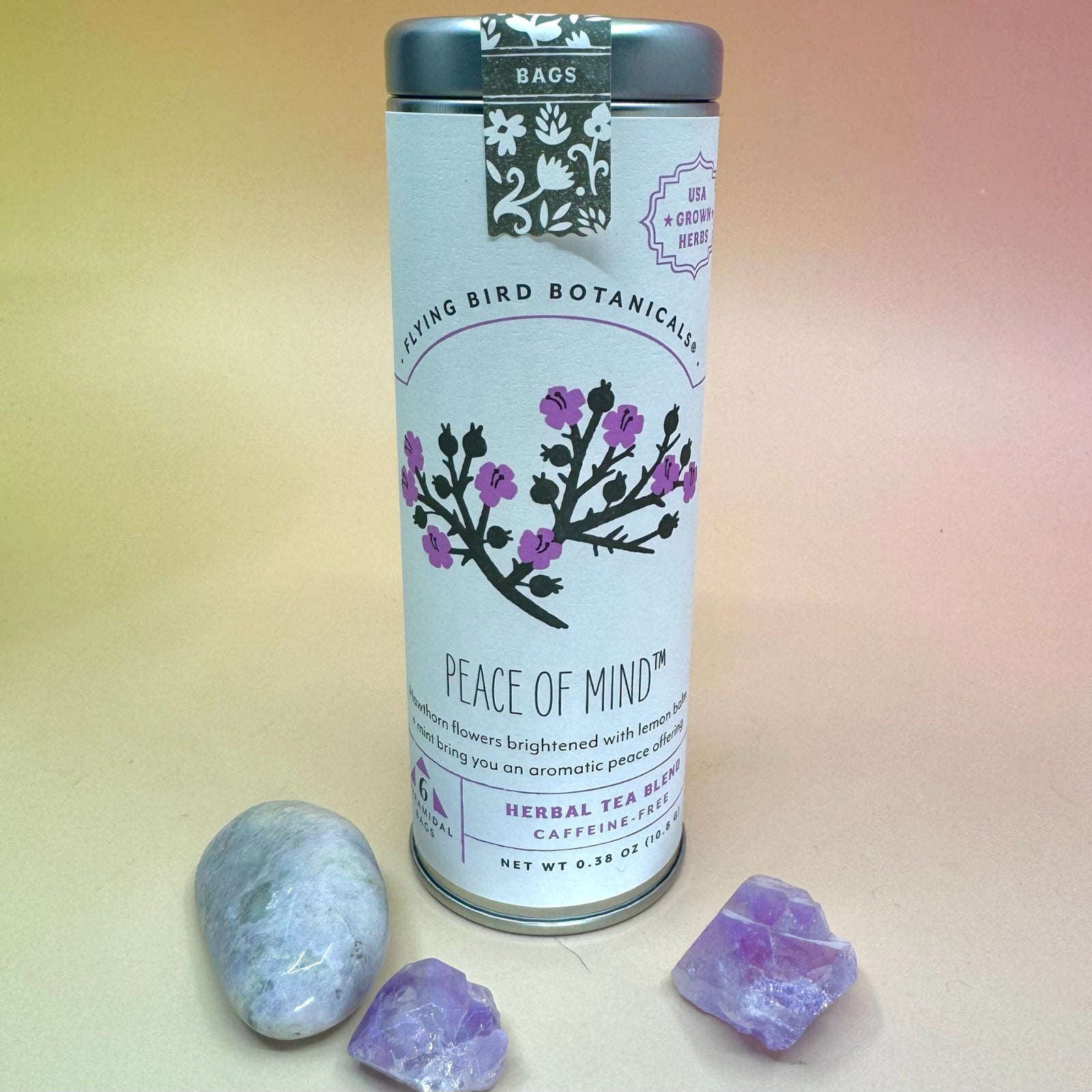 The Peace of Mind 6 Tea Bag Tin o a pink and yellow background surrounded by crystals.