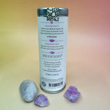 The Peace of Mind 6 Tea Bag Tin o a pink and yellow background surrounded by crystals, showing off the back.