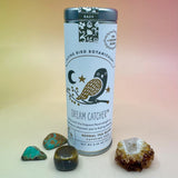 The Dream Catcher 6 Tea Bag Tin on a pink and yellow background surrounded by small crystals.