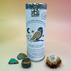 The Dream Catcher 6 Tea Bag Tin on a pink and yellow background surrounded by small crystals.