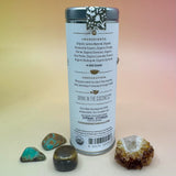 The Dream Catcher 6 Tea Bag Tin on a pink and yellow background surrounded by small crystals, showing off the back.