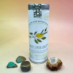 The White Lemon Ginger 6 Tea Bag Tin on a pink and yellow background surrounded by different small crystals.