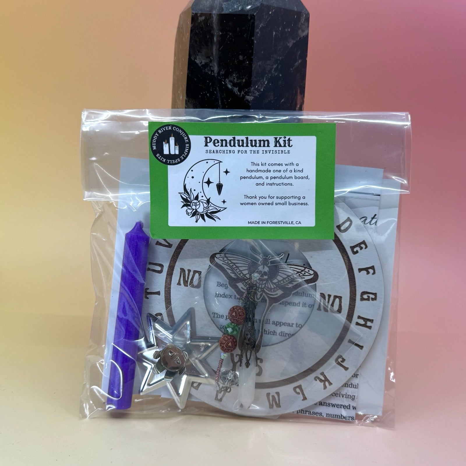 The Pendulum Kit against a crystal tower on a pink and yellow background.