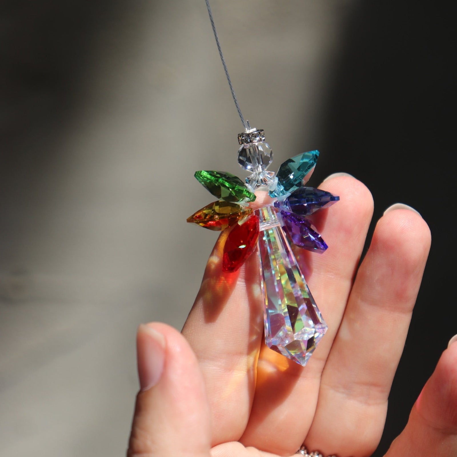 Someone holding the Crystal Chakra Guardian Angel in front of the ligt.