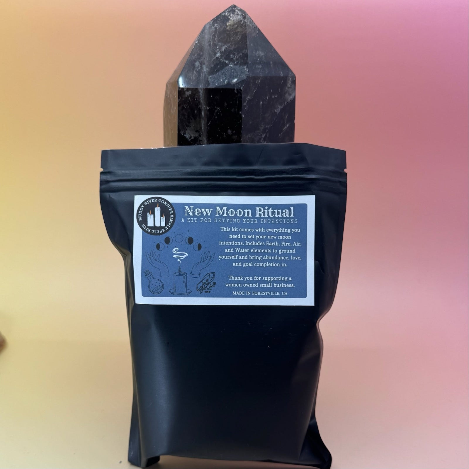 The New Moon Ritual Kit in front of a crystal tower on a pink and yellow background.