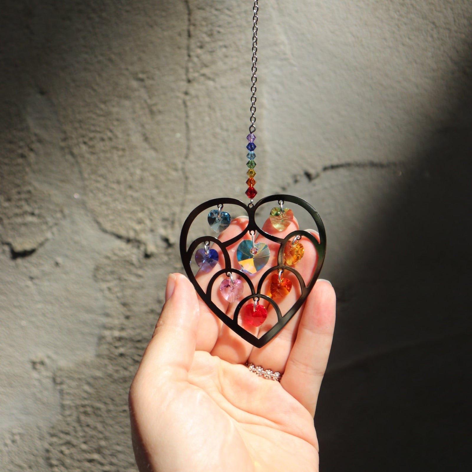 Someone holding the Heart of Hearts Chakra Ornament in the sunlight.