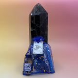 The protection Prayer Mojo Witchy Spell Bag against a crystal tower on a pink and yellow background.