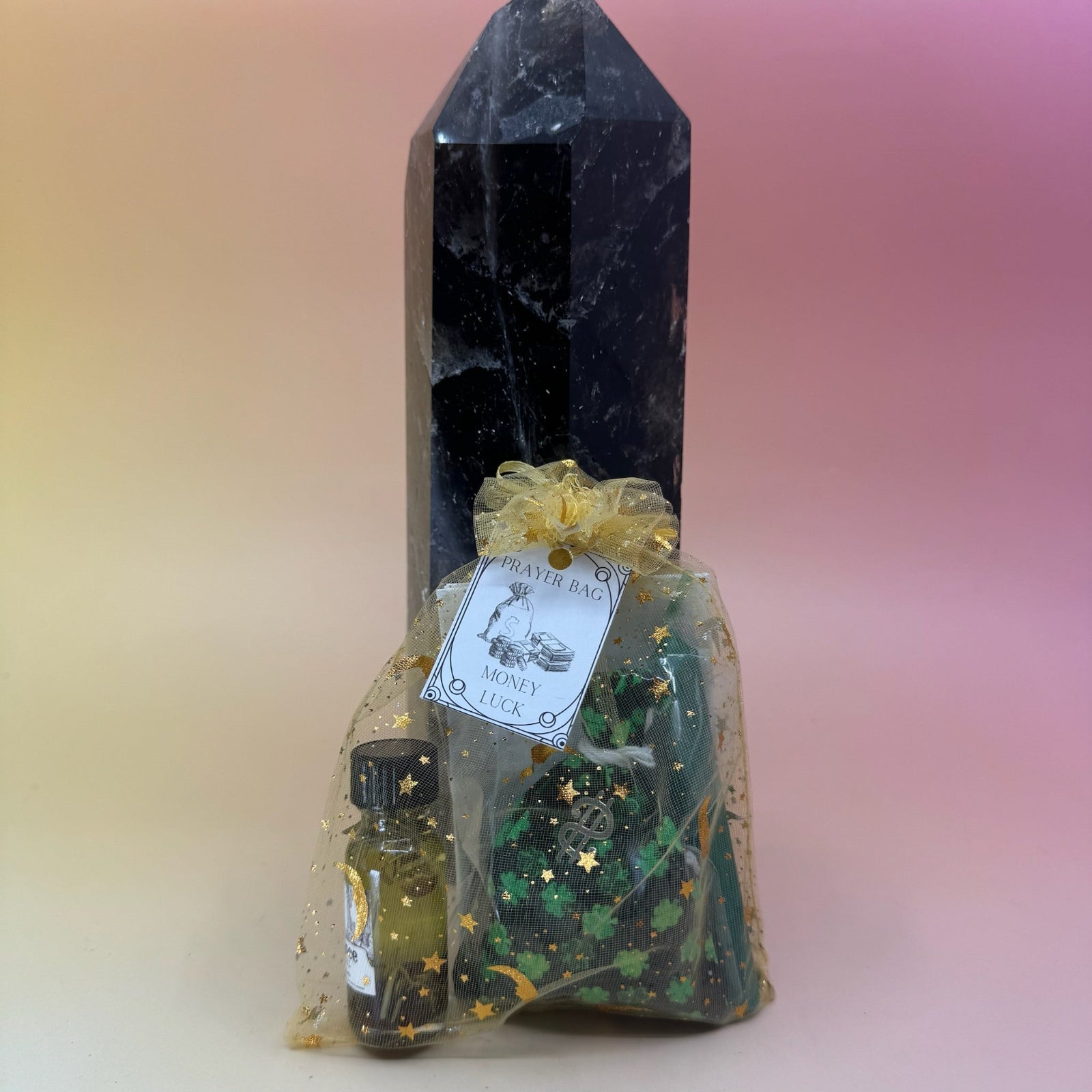 The money luck Prayer Mojo Witchy Spell Bag against a crystal tower on a pink and yellow background.