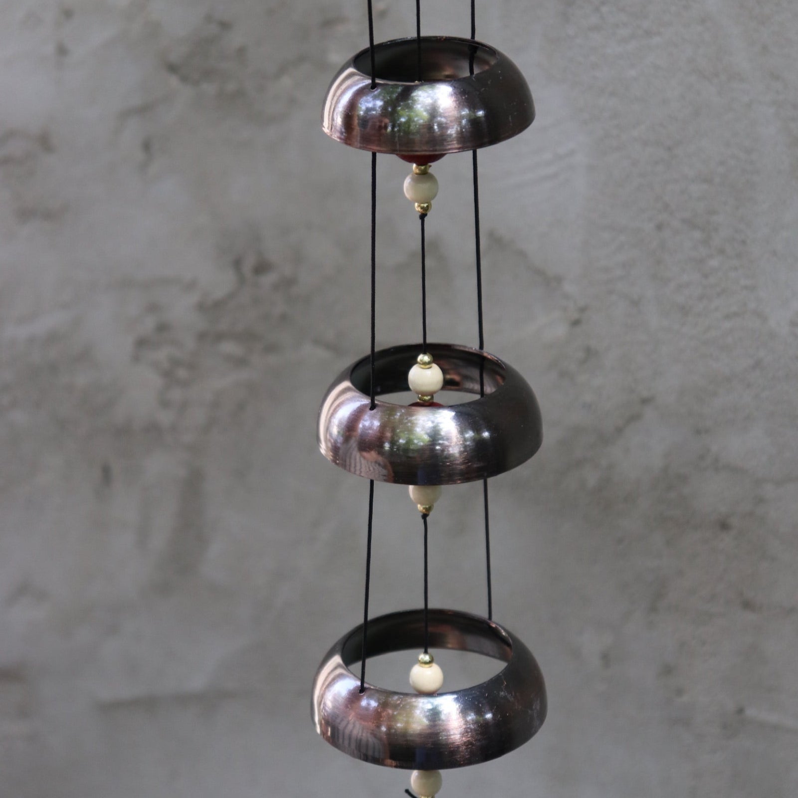 An up-close image of the Encore Copper Temple Bells in front of a white concrete wall.