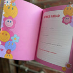 Someone holding a Daily Gratitude Journal open in front of a wooden background, showing off the pages.