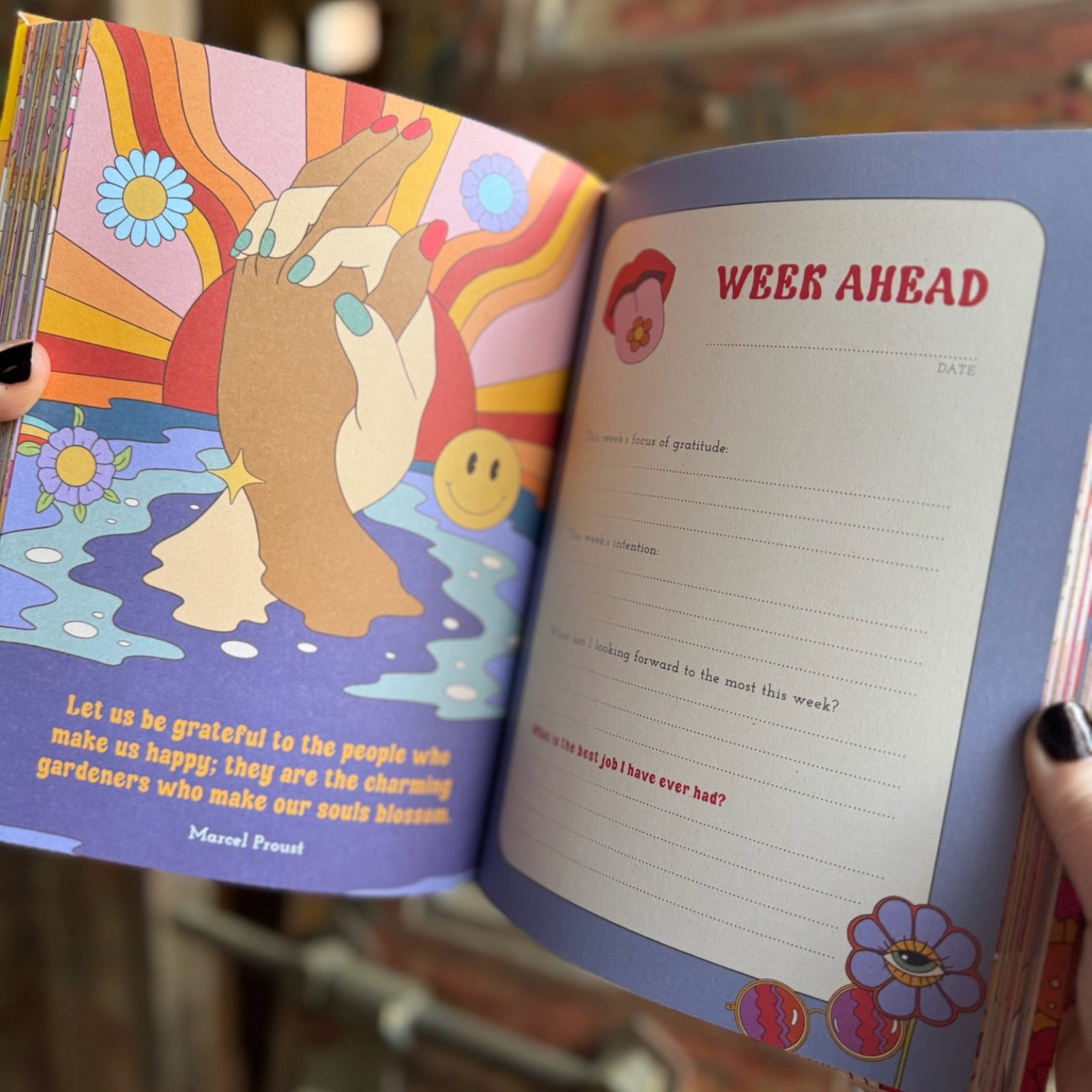 Someone holding a Daily Gratitude Journal open in front of a wooden background, showing off the pages.