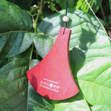 An up-close image of the red wooden clapper in front of green leaves.