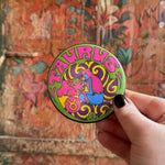 Someone holding the Taurus Astral Weekend Zodiac Magnet 3" Round in front of a wooden background.