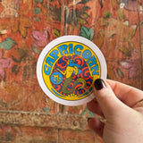 Someone holding the Capricorn Zodiac 3 Inch Sticker in front of a wooden background.
