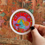 Someone holding the Cancer Zodiac 3 Inch Sticker in front of a wooden background.
