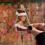 Someone holding the Mariah Carey Christmas Sticker in front of a wooden background.