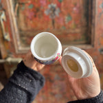 Someone holding the Grandma's Floral Ceramic Stash Jar in front of a wooden background, showing the inside.