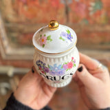 Someone holding the Grandma's Floral Ceramic Stash Jar in front of a wooden background, showing the top.
