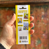 Someone holding the Fridge Eyes Magnets in front of a wooden background, showing off the back.