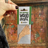 Someone holding the North Carolina Wood Sticker in front of a wooden background.