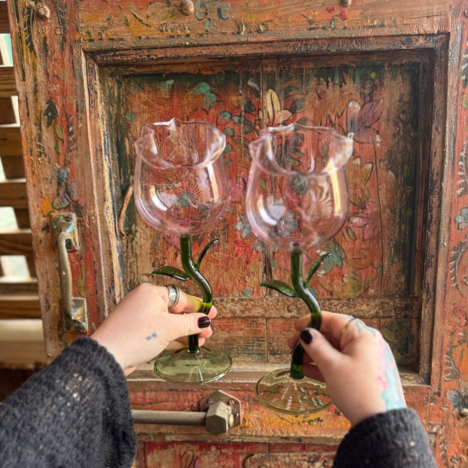 Someone holding the Rose Wine Glasses Set of 2 in front of a wooden background.