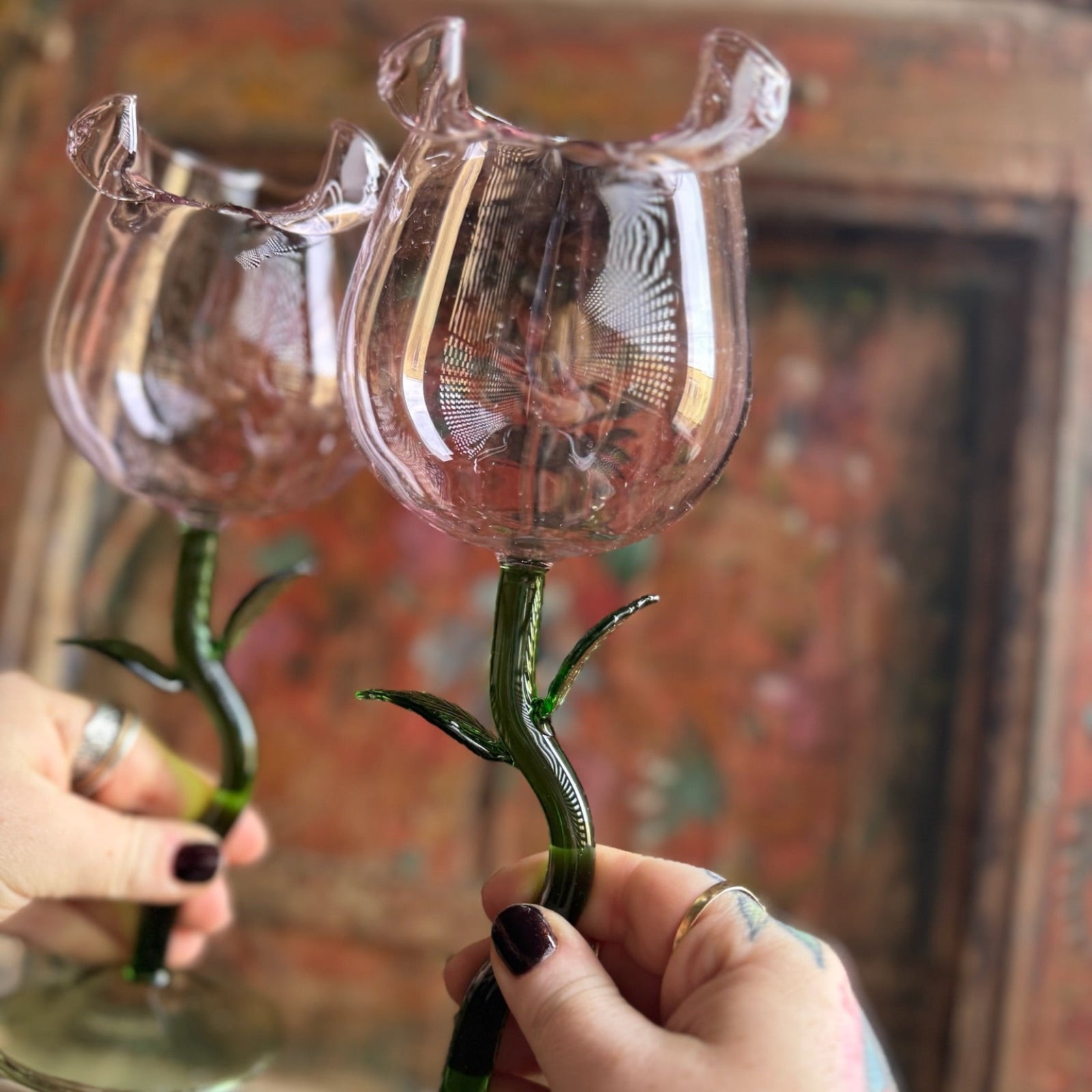 Someone holding the Rose Wine Glasses Set of 2 in front of a wooden background.