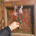 Someone holding a Rose Wine Glass in front of a wooden background.