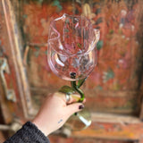 Someone holding a Rose Wine Glass in front of a wooden background.