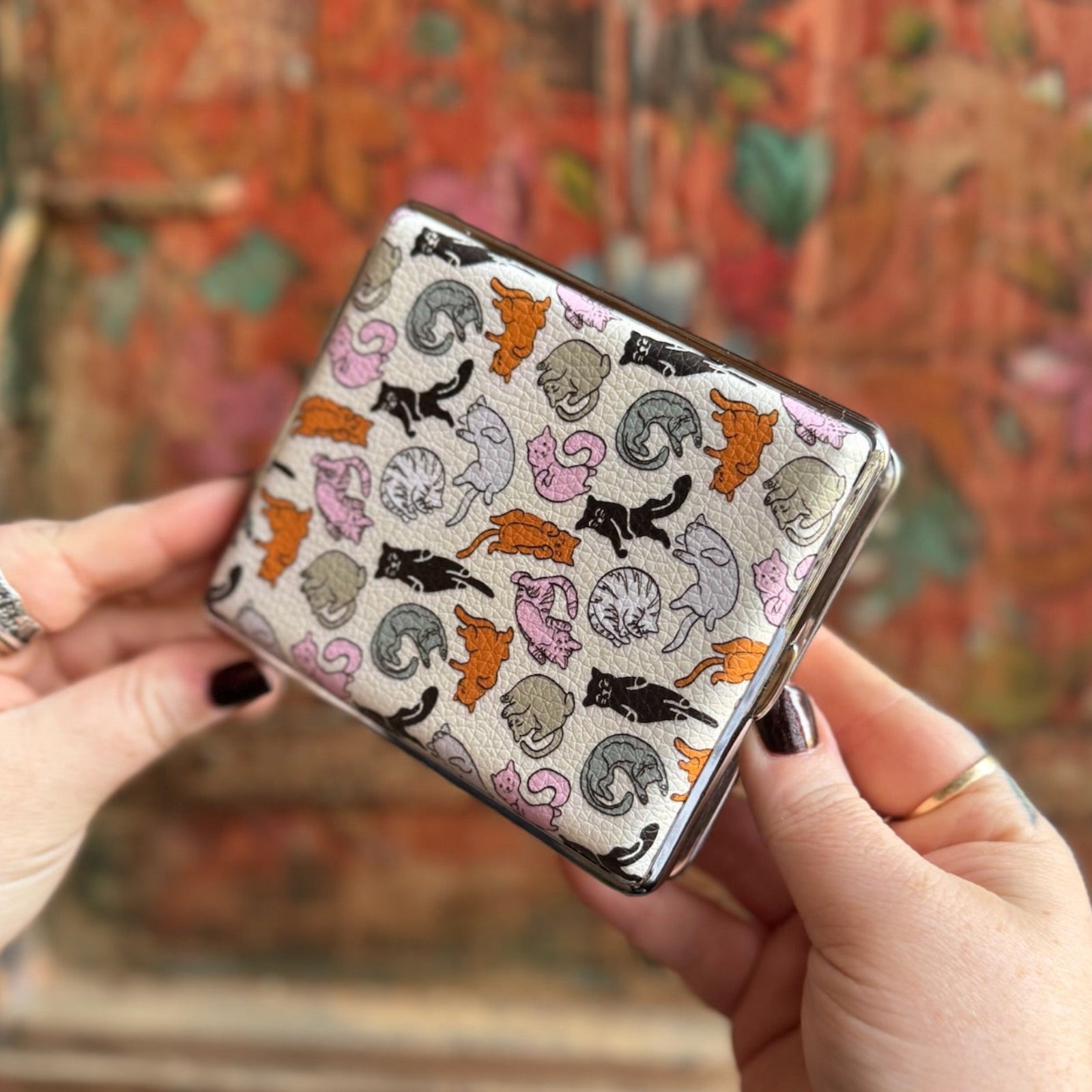 Someone holding the Cozy Cat Hardcover Cigarette Case in front of a wooden background.