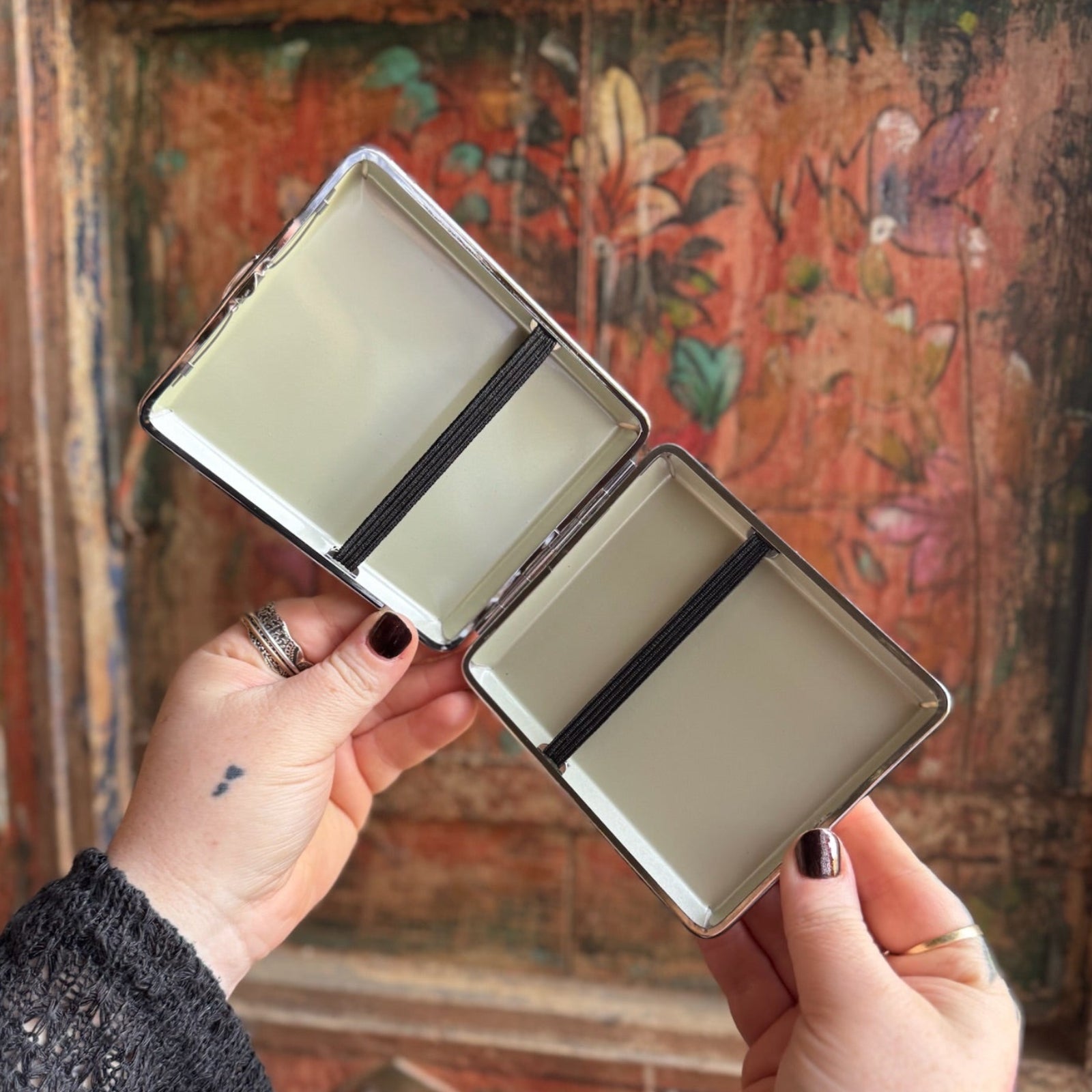 Someone holding the Cozy Cat Hardcover Cigarette Case in front of a wooden background, showing off the inside.
