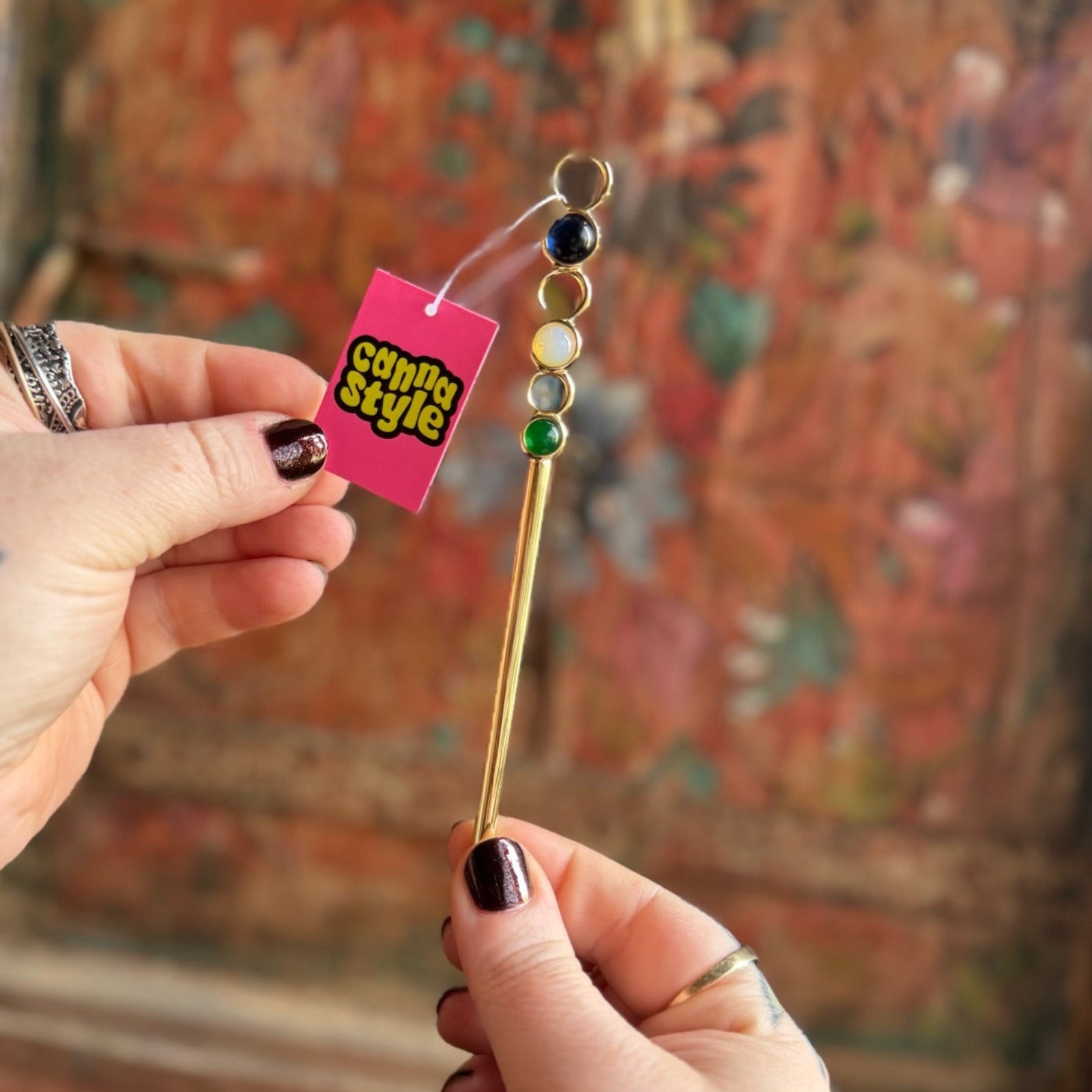 Someone holding the Stone Wand Cigarette Metal Holder & Packing Tool in front of a wooden background.
