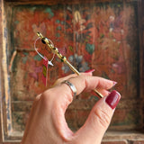 Someone holding the Stone Wand Cigarette Metal Holder & Packing Tool in front of a wooden background.