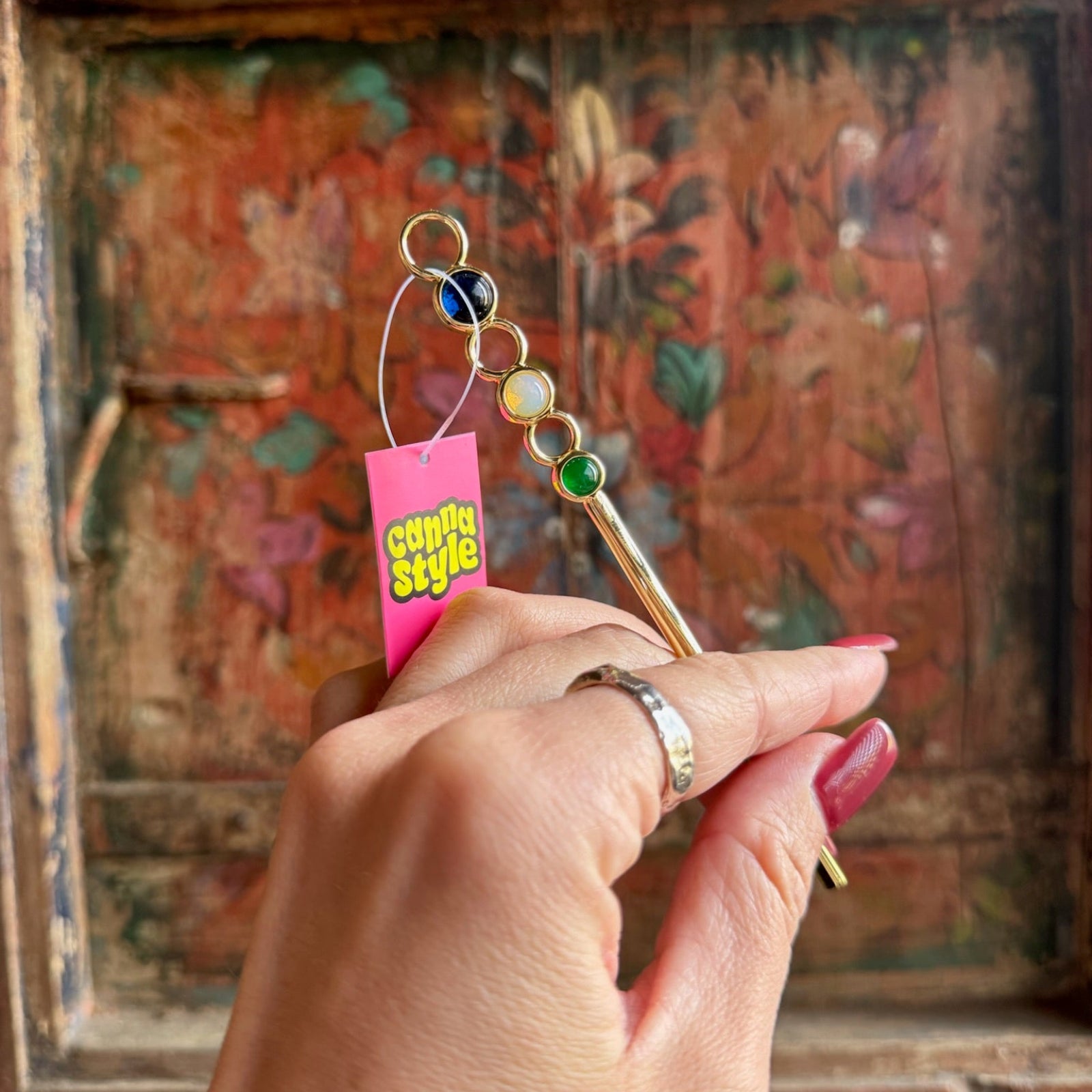 Someone holding the Stone Wand Cigarette Metal Holder & Packing Tool in front of a wooden background.