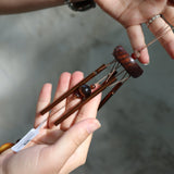 Someone holding the Tiger's Eye Precious Stones Wind Chime in front of a white wall.
