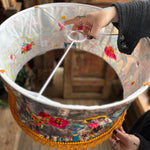 Someone holding the Cowgirl Collage Lamp Shade in front of a wooden background.