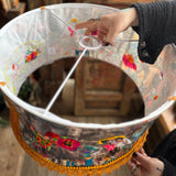 Someone holding the Cowgirl Collage Lamp Shade in front of a wooden background.