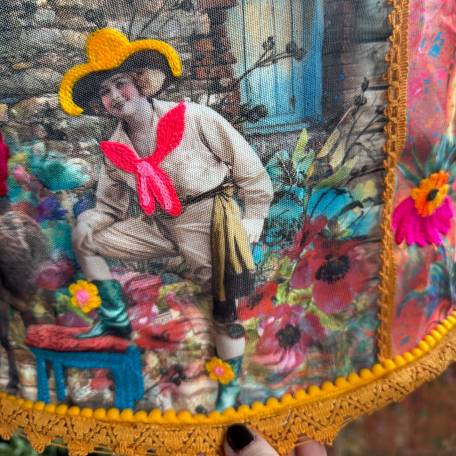An up-close image of someone holding the Cowgirl Collage Lamp Shade in front of a wooden background.