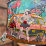 An up-close image of someone holding the Cowgirl Collage Lamp Shade in front of a wooden background.