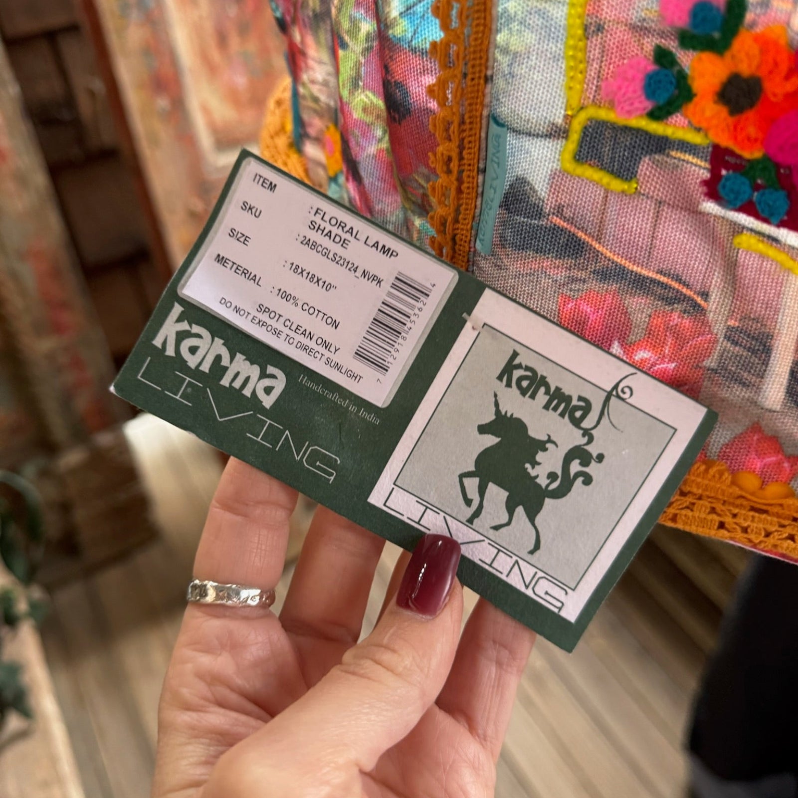 An up-close image of someone holding the Cowgirl Collage Lamp Shade tag in front of a wooden background.
