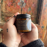 Someone holding the White Lodge Soy Wax 3 oz Candle in front of a wooden background.