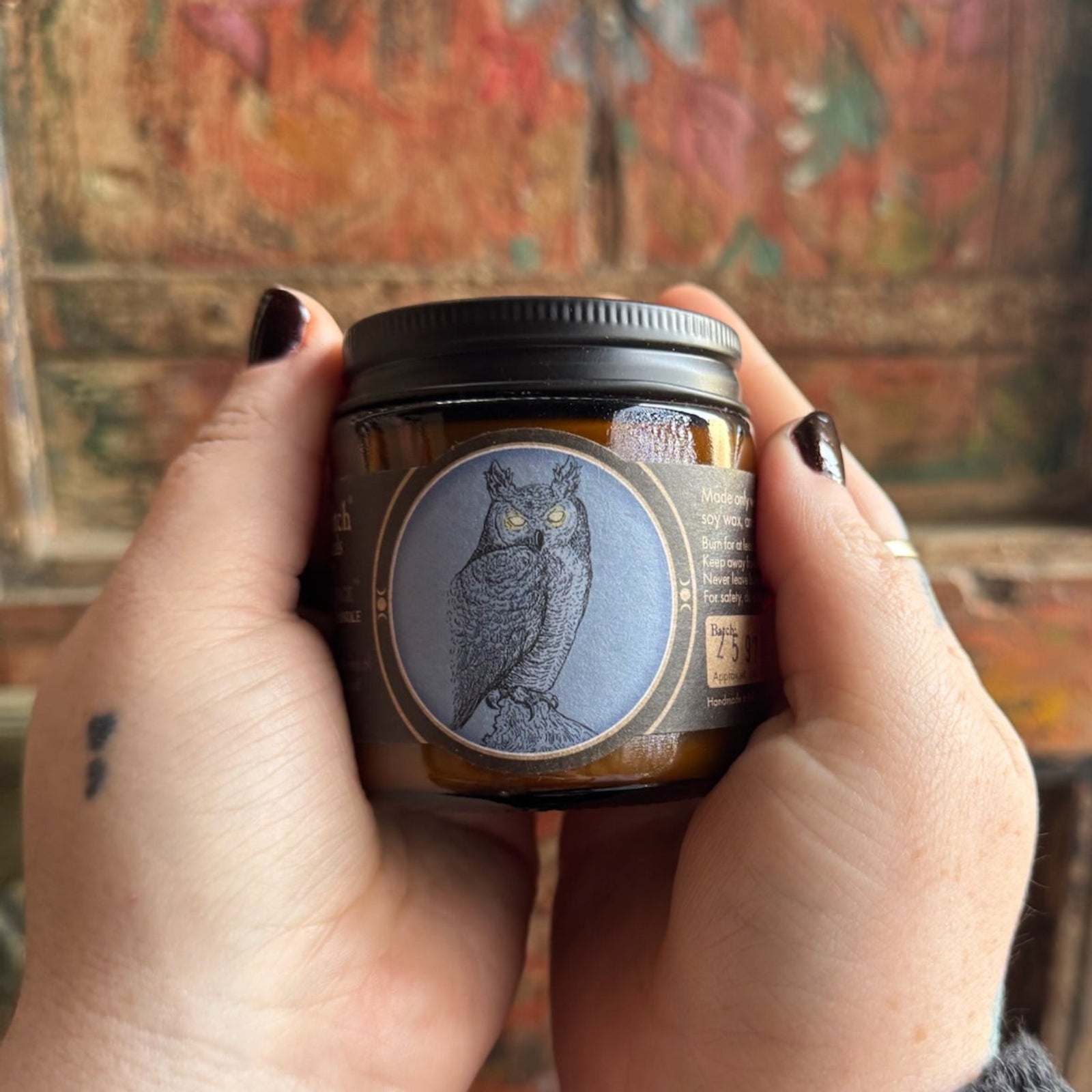 Someone holding the White Lodge Soy Wax 3 oz Candle in front of a wooden background.