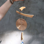 Someone holding the Small Emperor Gong Wind Chime in front of a white wall.