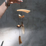 Someone holding the Small Emperor Gong Wind Chime in front of a white wall.