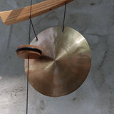 An up-close image of the Small Emperor Gong Wind Chime in front of a white wall.