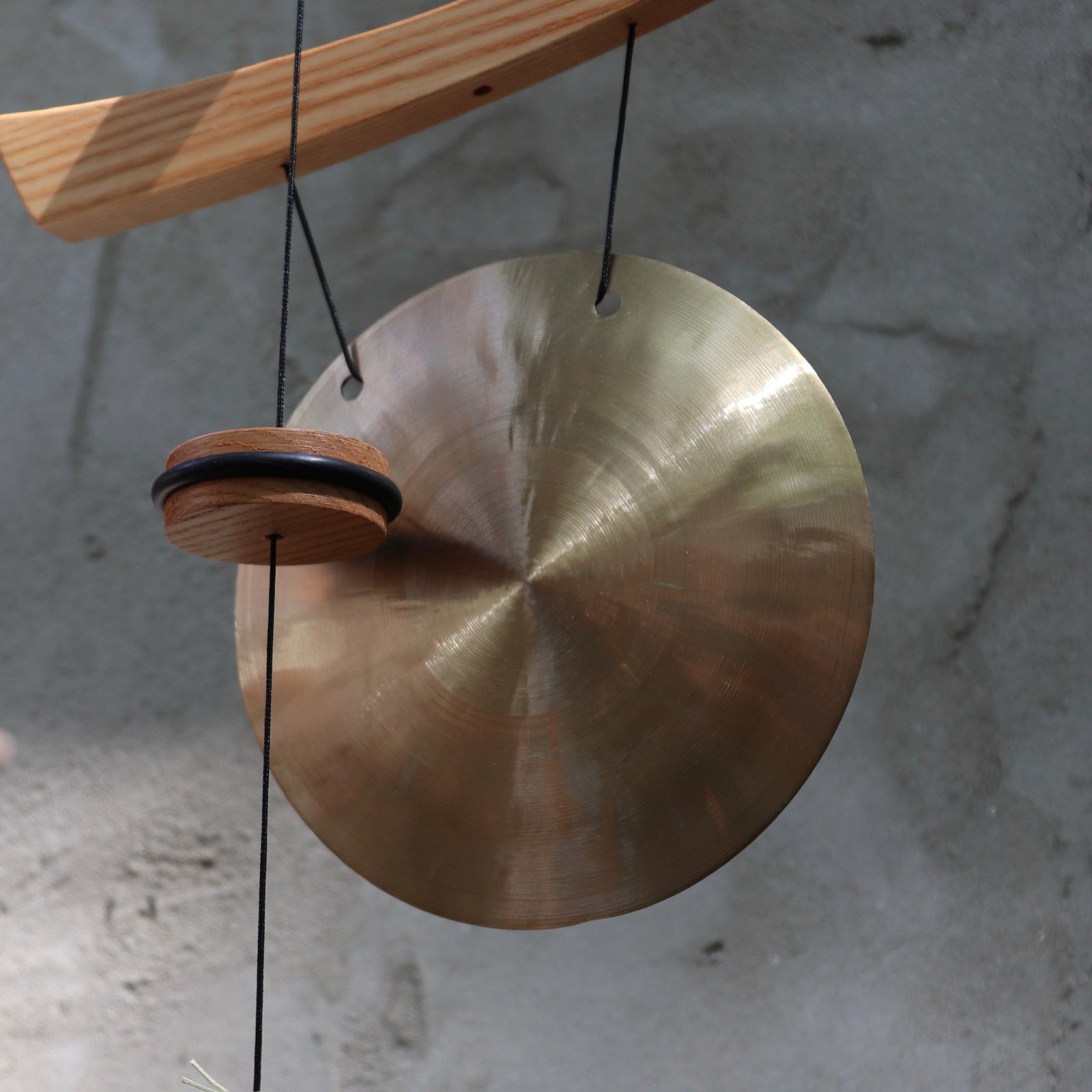 An up-close image of the Small Emperor Gong Wind Chime in front of a white wall.