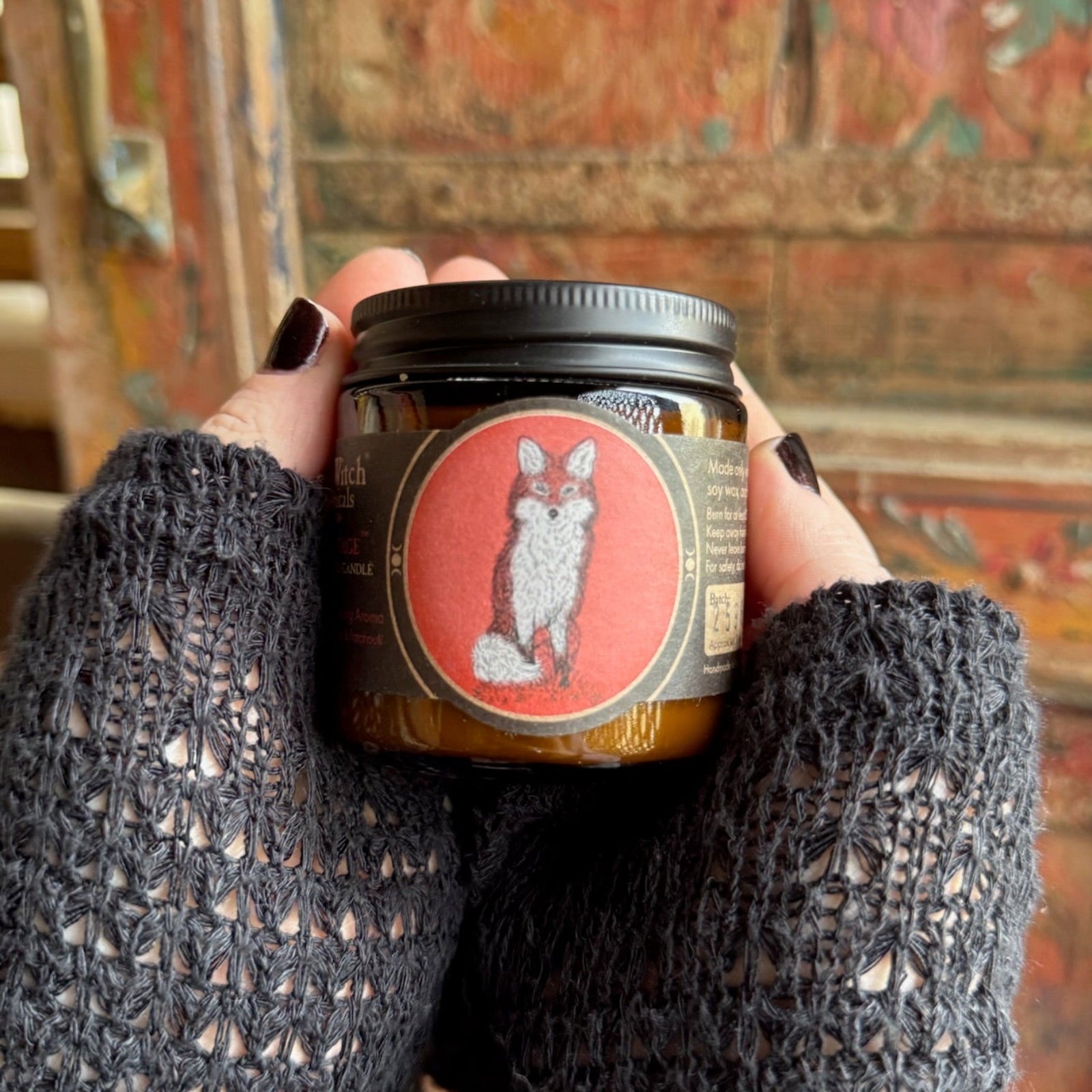 Someone holding the Hermitage Soy Wax 3 oz Candle in front of a wooden background.